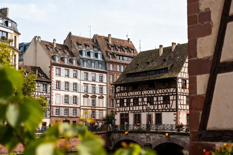 Bâtiments historiques à colombages et pont, Strasbourg, lumière douce, ciel clair, arbres légèrement flous.