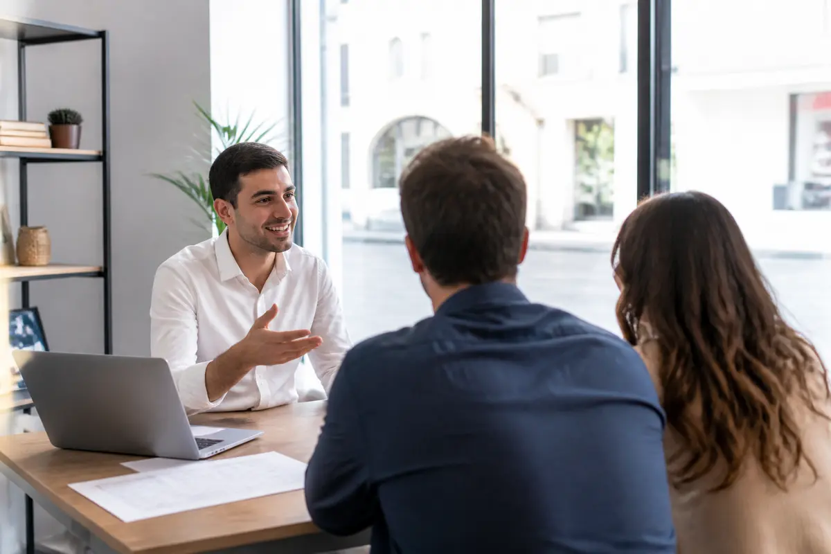 Agent d'ADL Immobilier discutant avec un couple dans un bureau lumineux