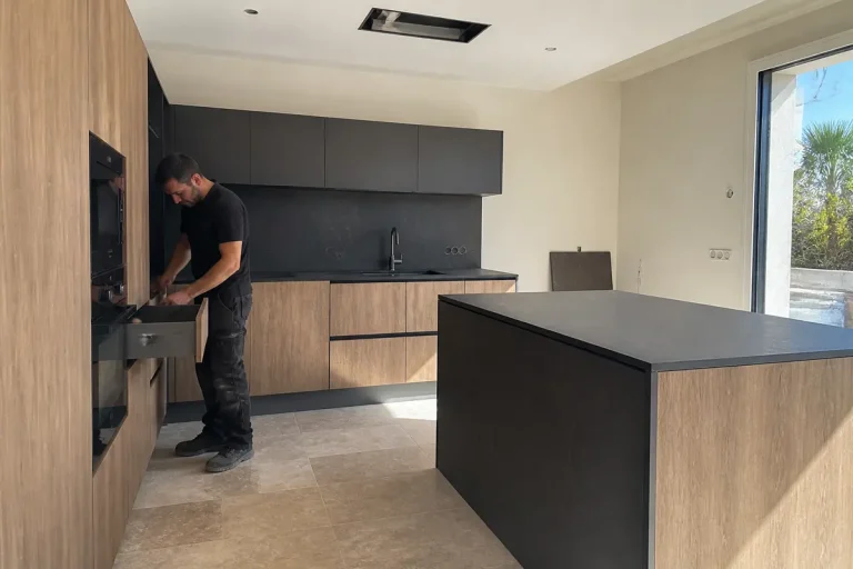 Un homme installe des équipements modernes dans une cuisine Coream Cuisine en bois et noir