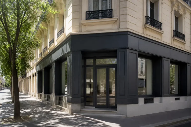 Coin d’un immeuble haussmannien avec vitrine, bureau de l'agence Immobilière Pujol.