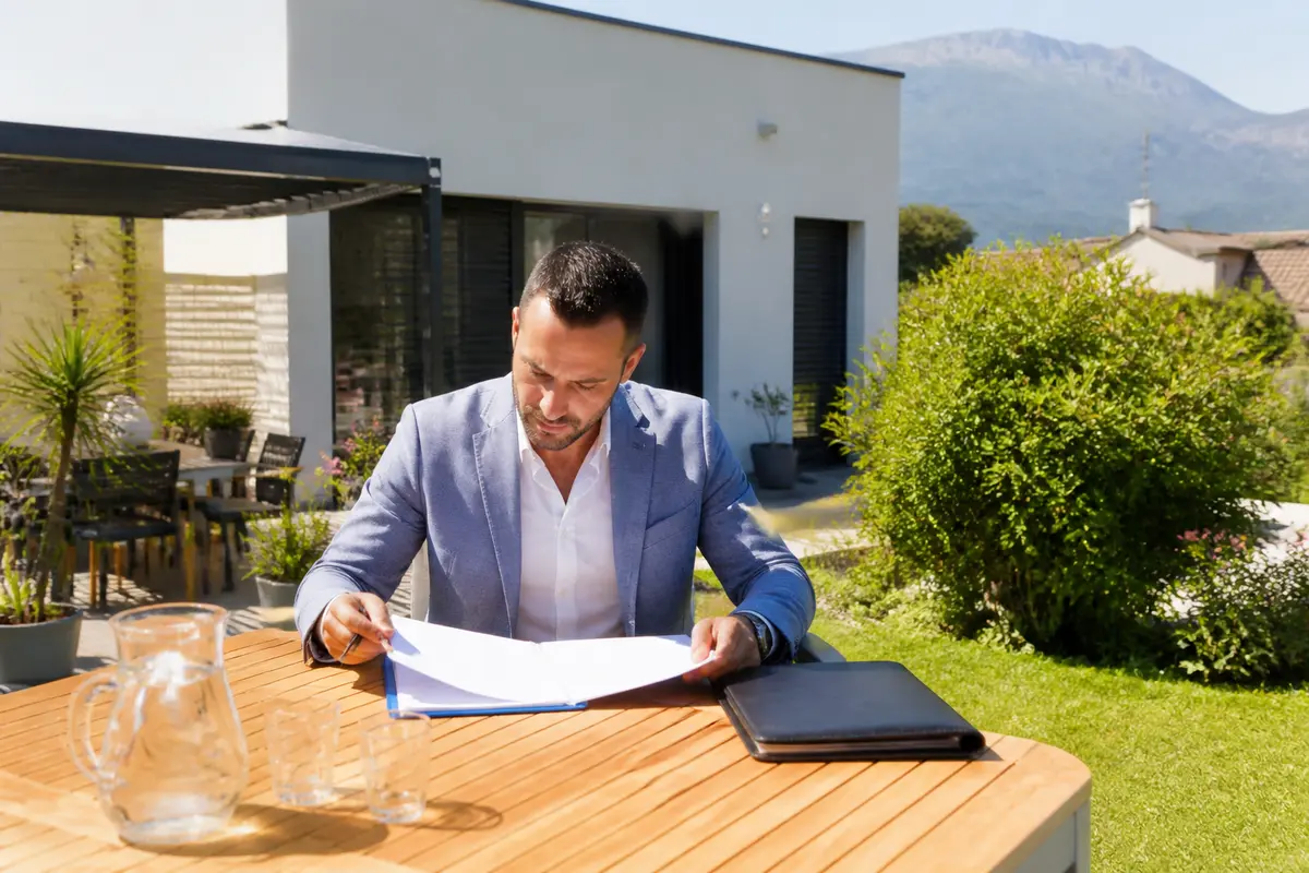 Agent lisant des documents immobiliers dans un jardin pour l'agence immobilière Spy Immo