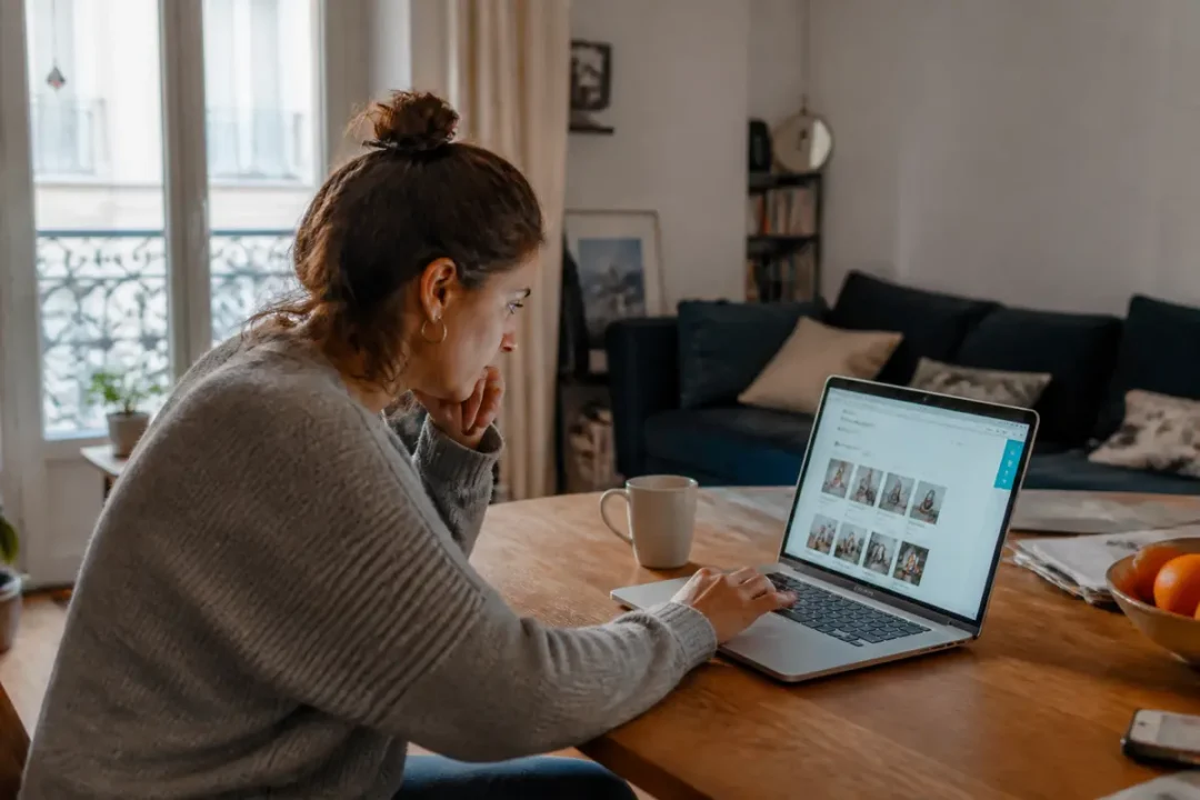 Femme travaillant sur ordinateur pour le projet Annah dans un salon cosy et lumineux