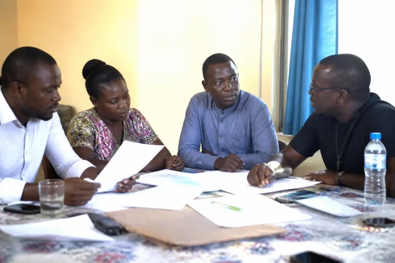 Quatre personnes discutant autour de documents, réunion organisée par unarc.
